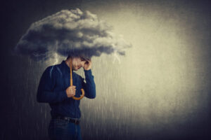 Pessimistic man, standing under rain, suffering anxiety as holding an umbrella thunderstorm cloud over head. Concept of memory loss and dementia disease. Alzheimer's losing brain and memory function.