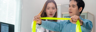 female doctor showing male patient how to use resistance band
