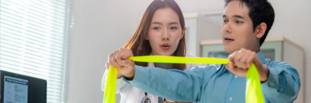 female doctor showing male patient how to use resistance band