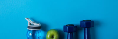 Water bottle, apple, and weights on a blue background