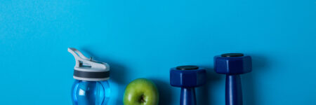 Water bottle, apple, and weights on a blue background
