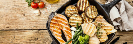 grilled salmon, chicken, asparagus, and broccoli on a skillet