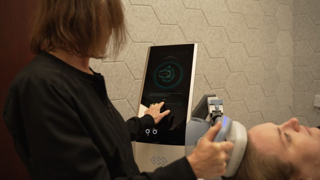 Denise holding Exomind TMS device and changing settings