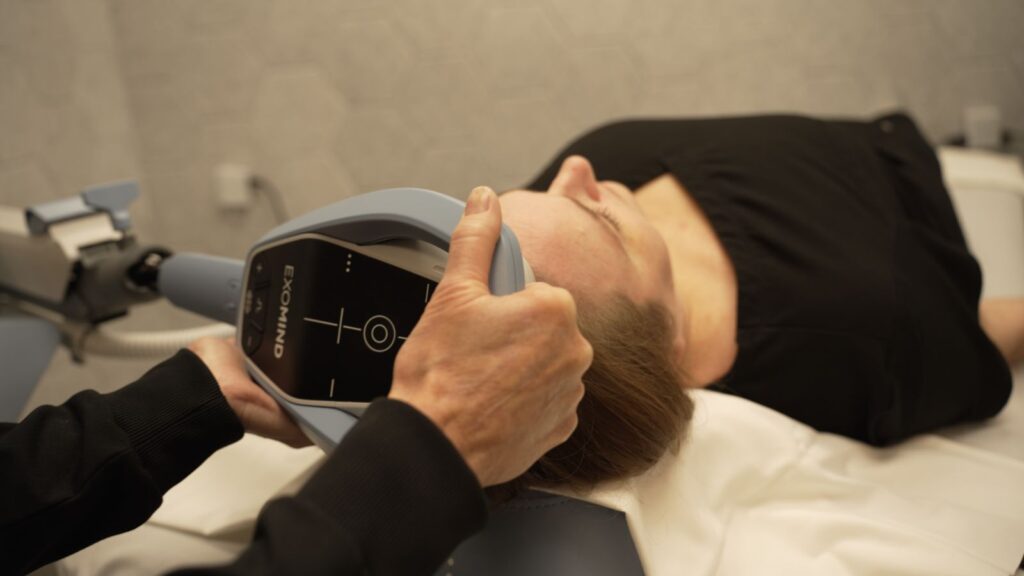 Nurse holding Exomind TMS device to users head with both hands