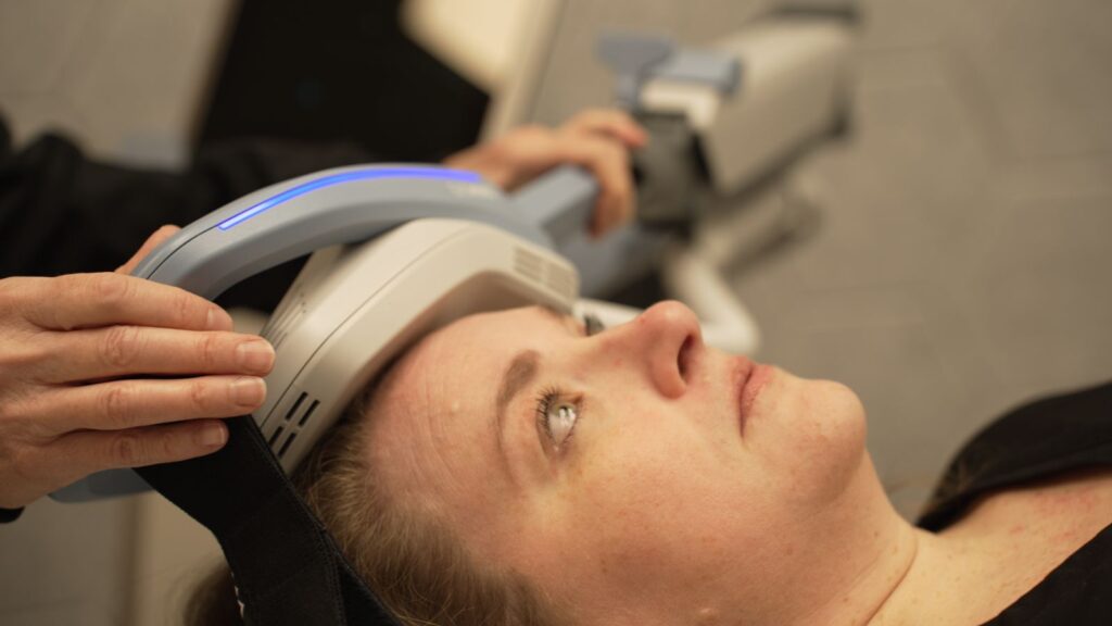Patient with TMS therapy device on applied to head