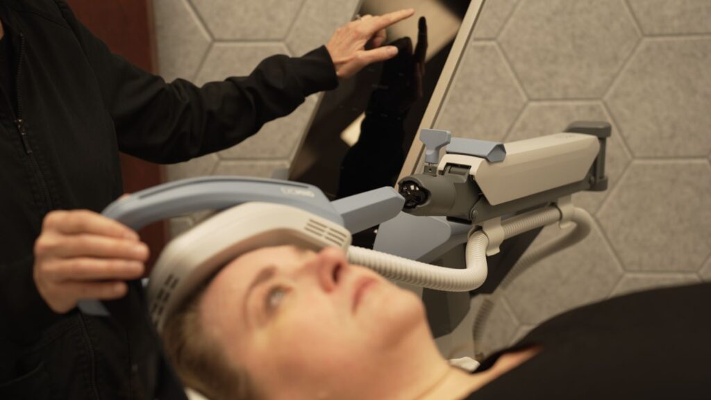 Nurse holding Exomind TMS device to users head